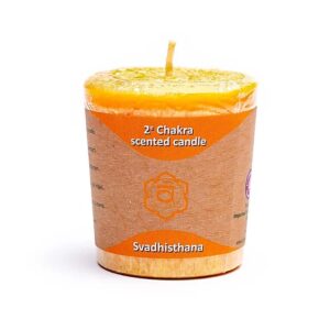 Un portocaliu „Lumânare Votivă Parfumată Chakra 2” etichetat „2nd Chakra scented candle” cu textul „Svadhisthana” în partea de jos. Lumânarea este învelită în plastic transparent și are o etichetă maro simplă cu text.