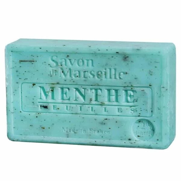 Un baton dreptunghiular de săpun verde deschis cu pete închise la culoare, în relief cu „Savon de Marseille, Menthe Feuilles” și „Made in France”. Acest Săpun Natural Marseille cu Frunze de Mentă pare să fie făcut cu frunze de mentă.