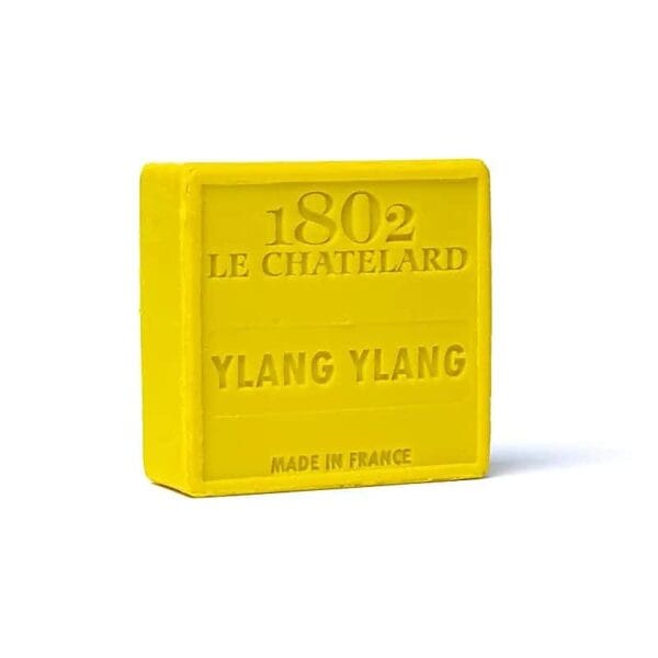 Un săpun pătrat galben cu textul „1802 Le Chatelard Ylang Ylang” și „Made in France” în relief. Acest Săpun Natural Marsilia cu Ylang-Ylang emană un parfum delicat de ylang-ylang.